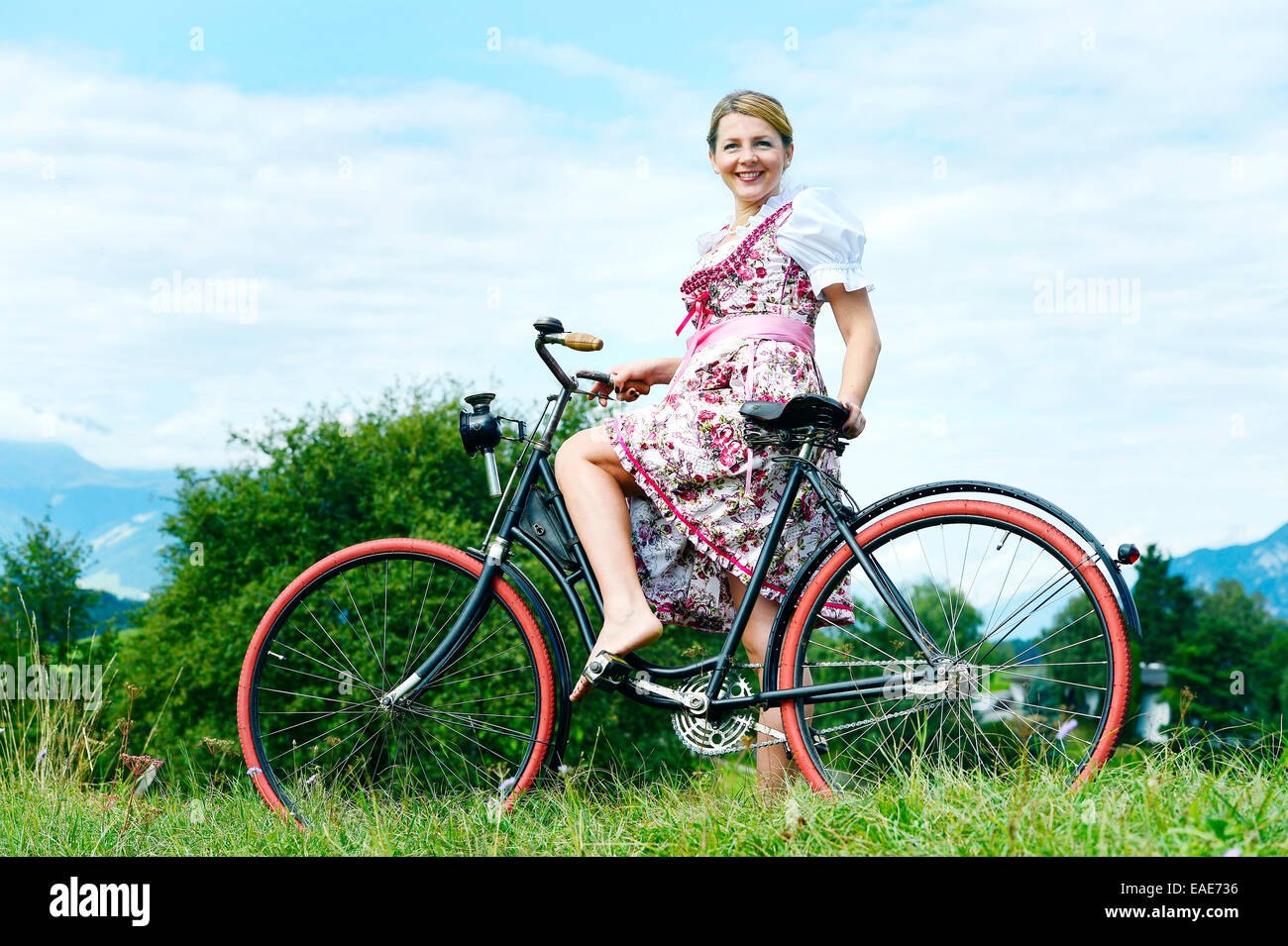 Woman wearing a dirndl on an old bicycle, Igls, Innsbruck, Tyrol, Austria Stock Photo