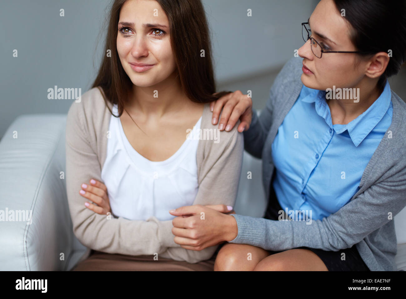 Female psychiatrist comforting young crying woman Stock Photo