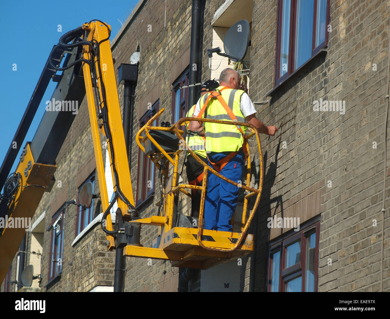 Tradesmen cement pointing the the exterior of a building hoisted up