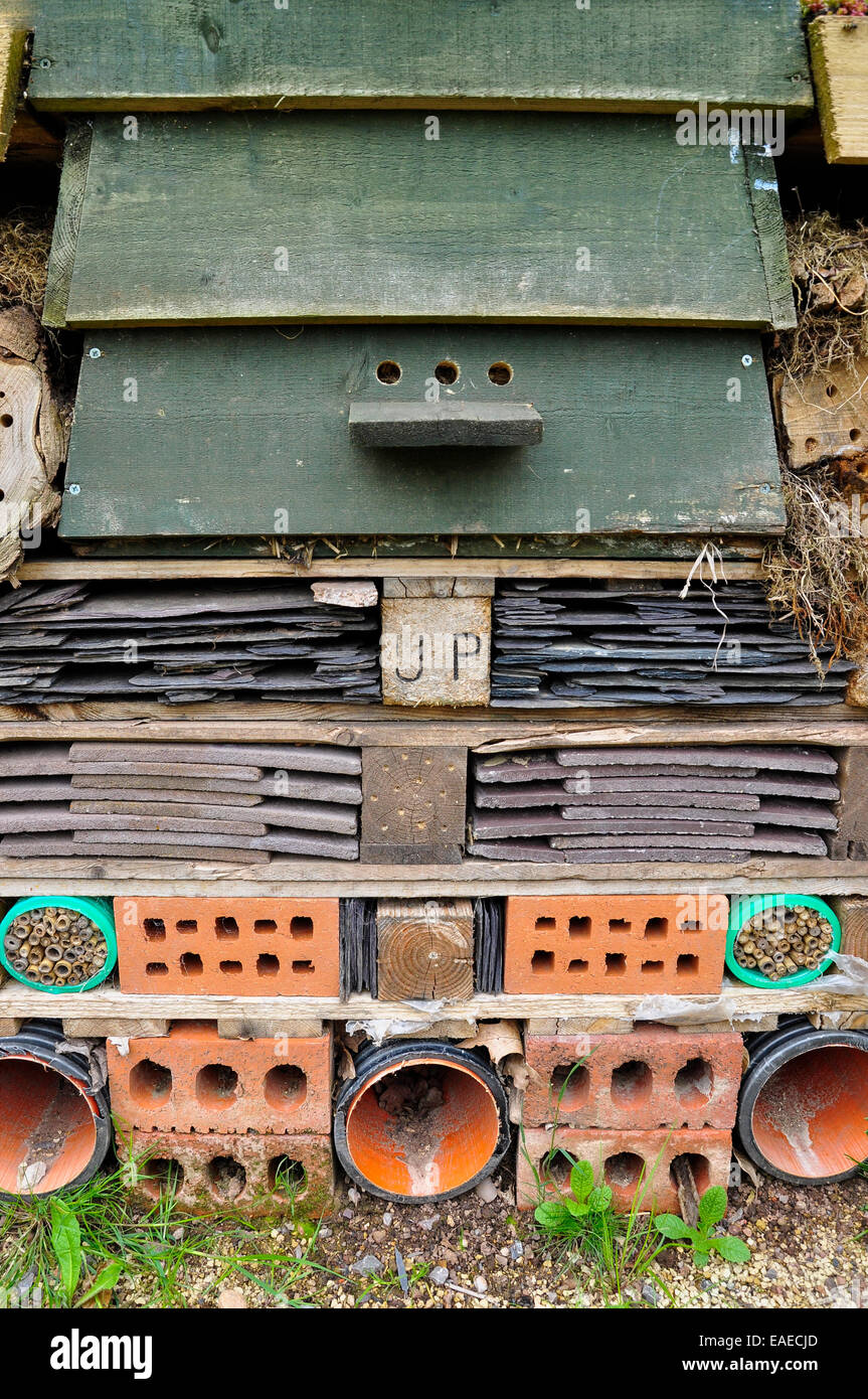 Bug hotel. Stack of old slates, roof tiles, bricks, pipes and natural materials forming a habitat for insects in a garden. Stock Photo
