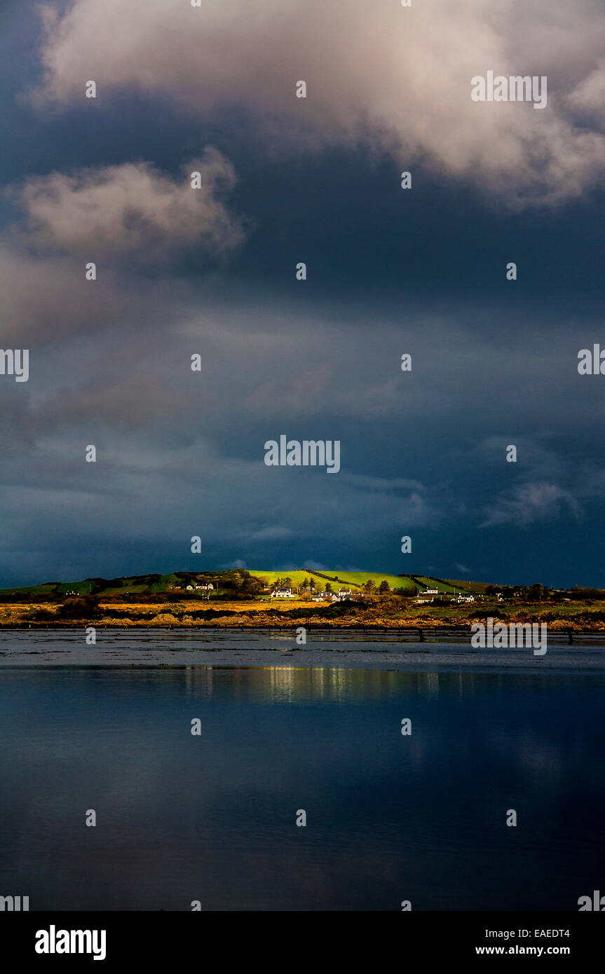 A shaft of sunlight catches houses in Ardara Donegal during a stormy