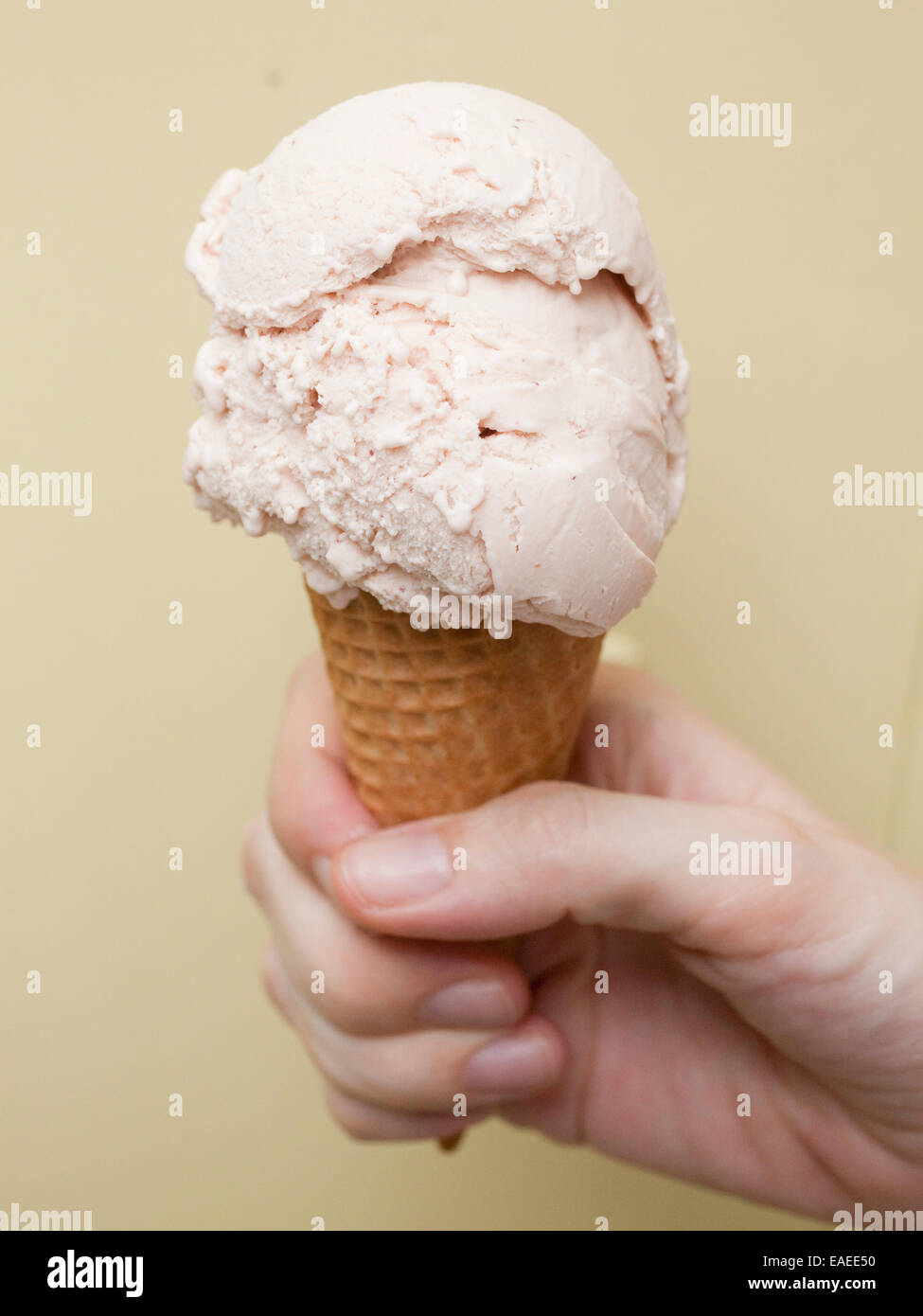 hand holding a Scoop of strawberry ice cream in waffle cone Stock Photo
