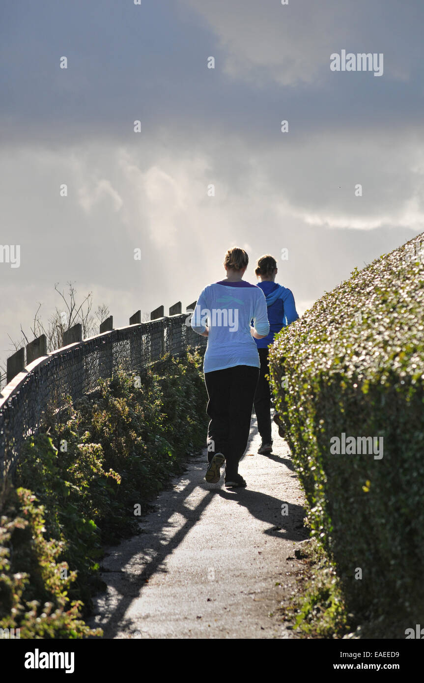 Two people running along a coastal path Stock Photo