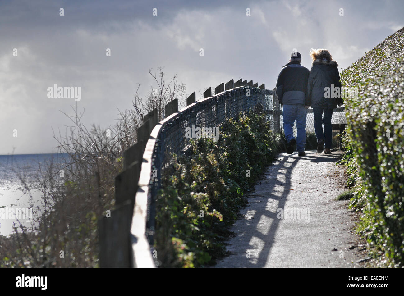 A couple walk along a coastal path Stock Photo