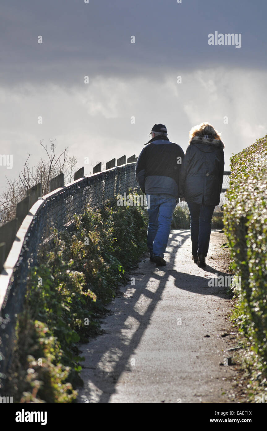 A couple walk along a coastal path Stock Photo