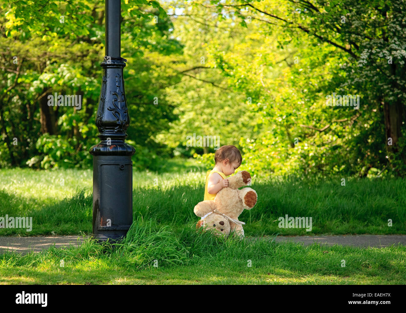 toddler 13 months old (mixed race Caucasian/Oriental Asian) exploring the outdoors carrying teddy bear Stock Photo