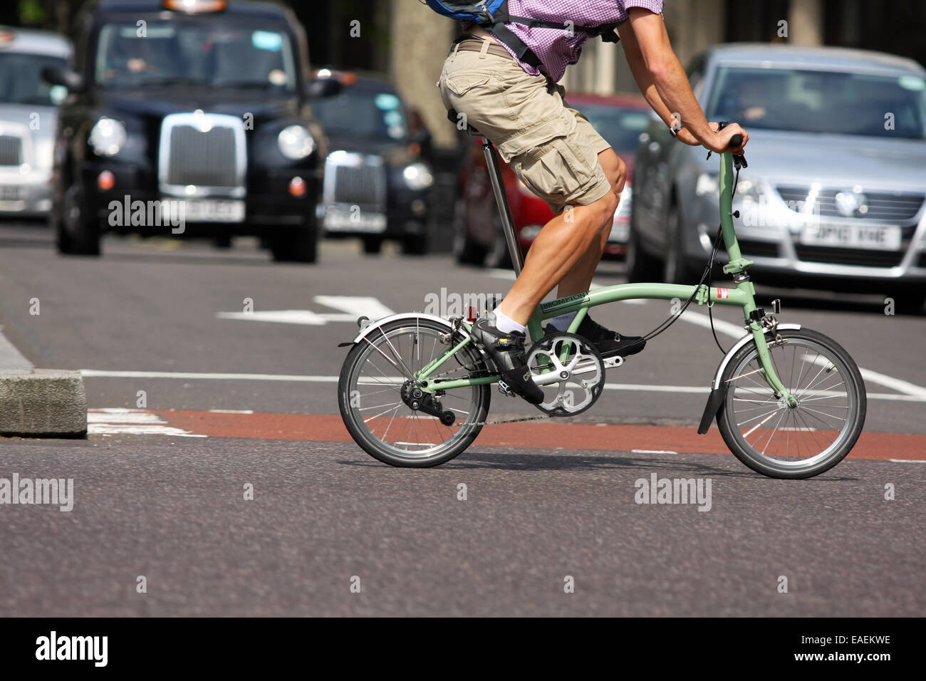 A cyclist riding a folding cycle across a junction in London Stock