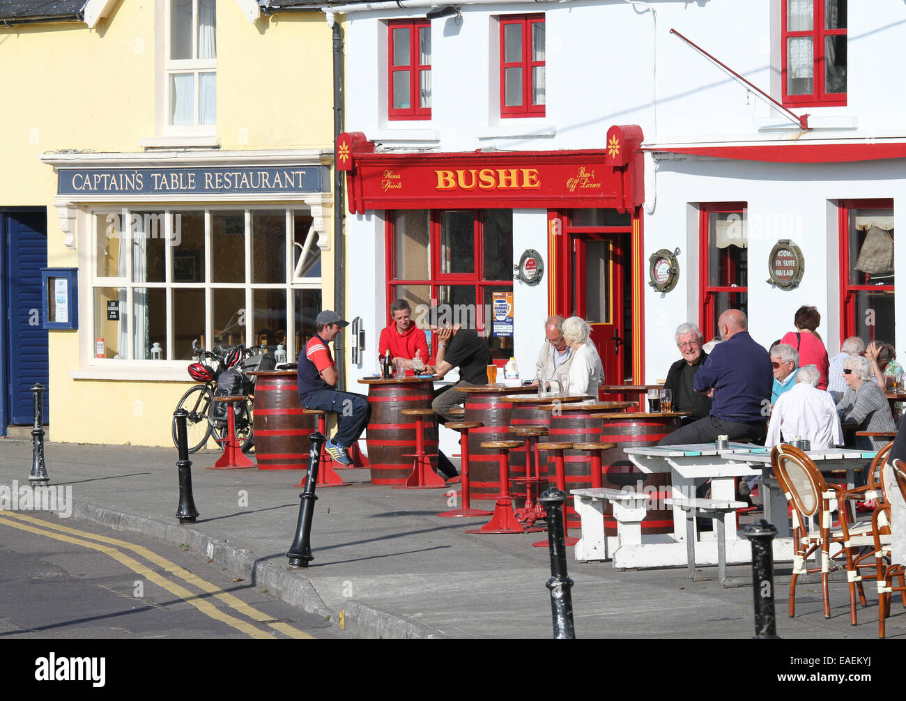 People and tourists sitting eating and drinking outside a public house in Ireland above the harbour at Baltimore West Cork County Cork Ireland Stock Photo