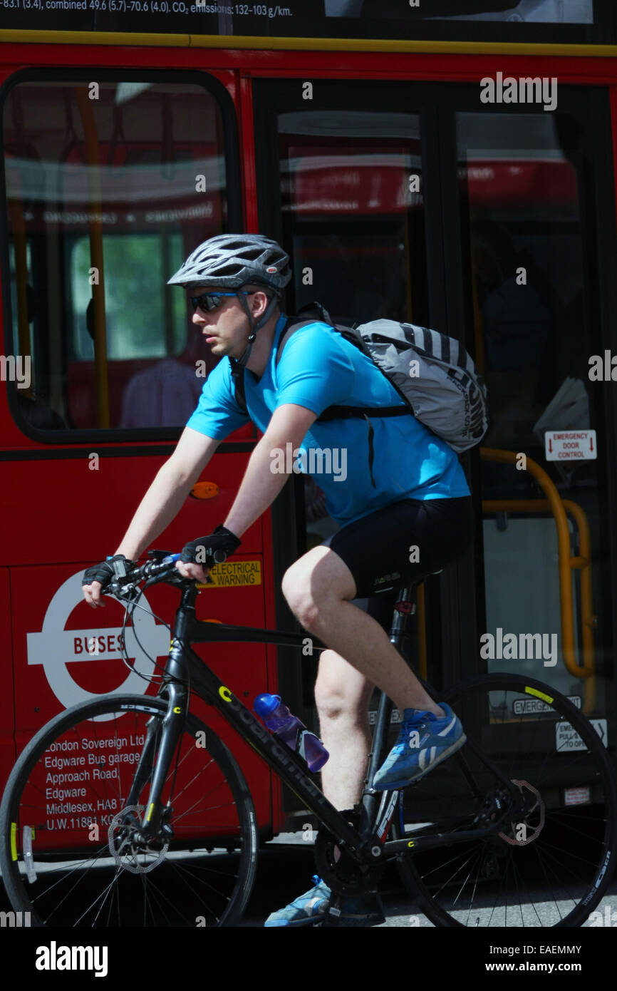 A cyclist traveling next to a London bus Stock Photo - Alamy