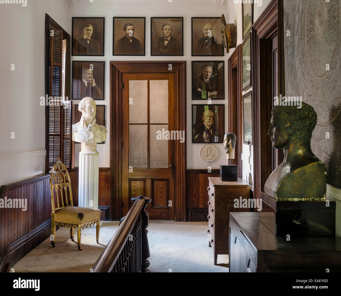 Early 20th century photographs on landing with velvet pile carpet, plaster bust of George Washington and glass panelled door Stock Photo