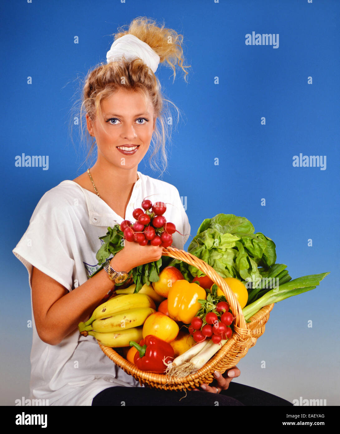 Blond woman with a basket full with fruits and vegetables Stock Photo