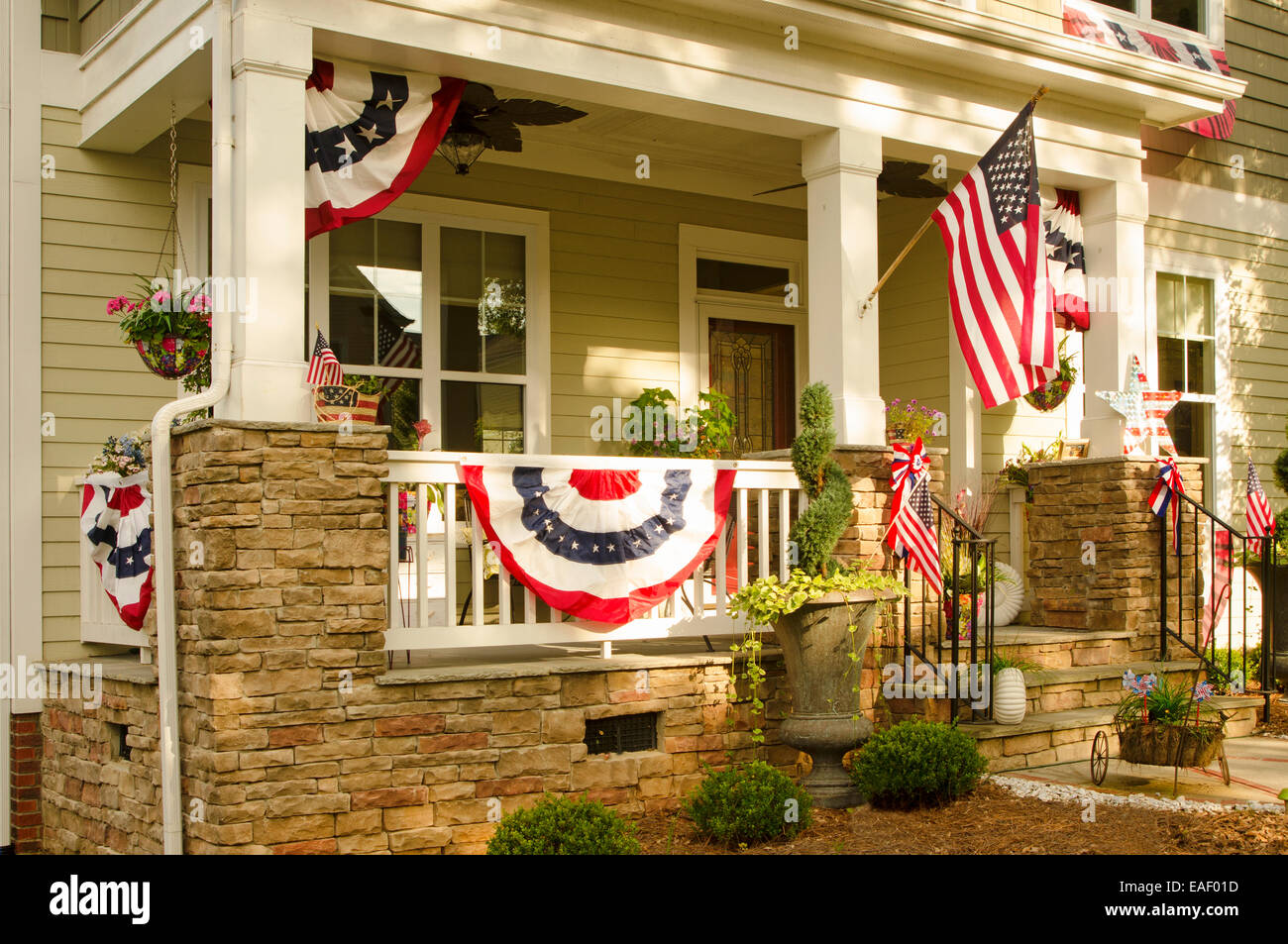An American Flag and buntings hang from a front porch of an upscale