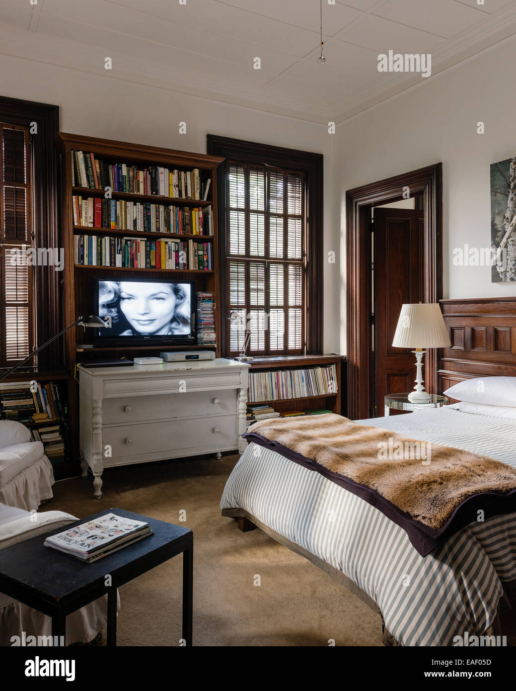 Flat screen tv above Swedish style chest of drawers in bedroom with