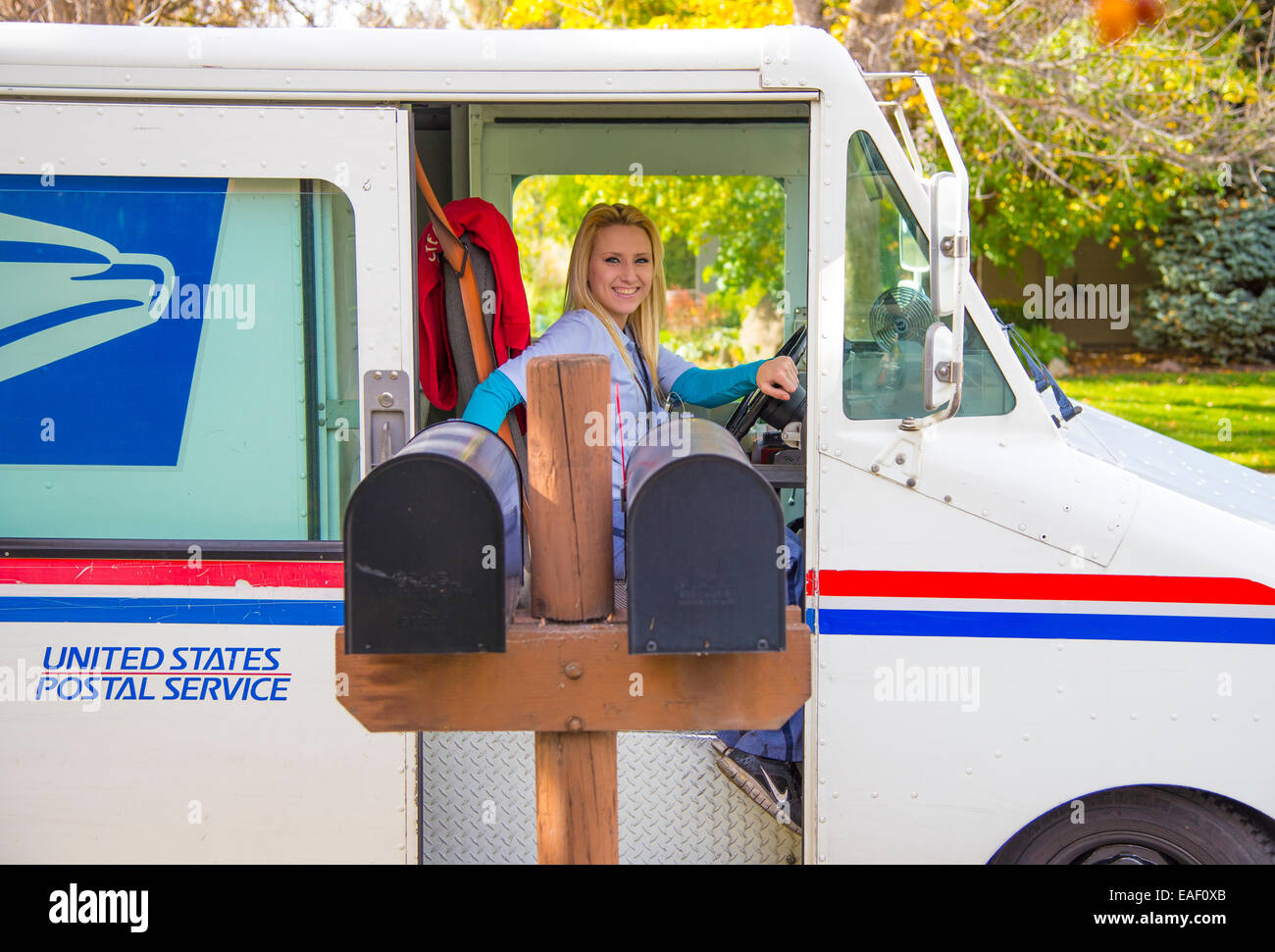 Female United States Postal Service carrier delivering mail in residential neighborhood. Boise, Idaho, USA Stock Photo