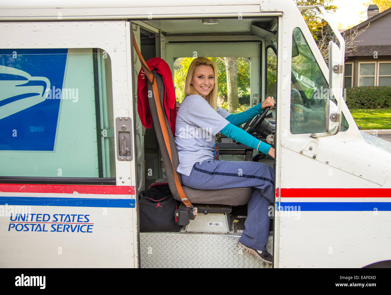Female United States Postal Service carrier delivering mail in residential neighborhood. Boise, Idaho, USA Stock Photo