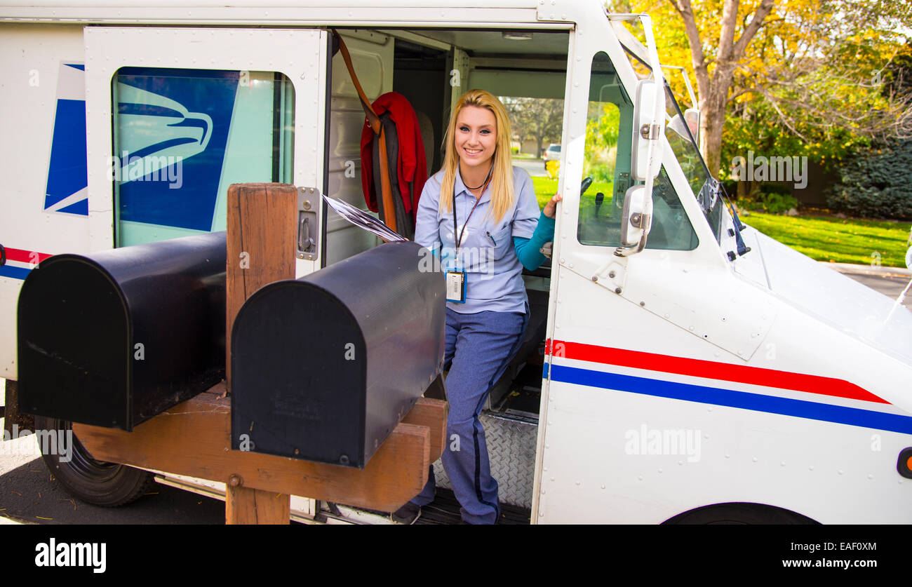 Female United States Postal Service carrier delivering mail in residential neighborhood. Boise, Idaho, USA Stock Photo