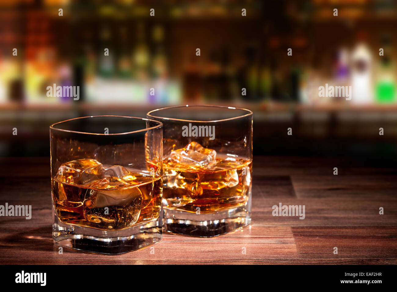 Whiskey drinks on wooden table with blur bar on background Stock Photo