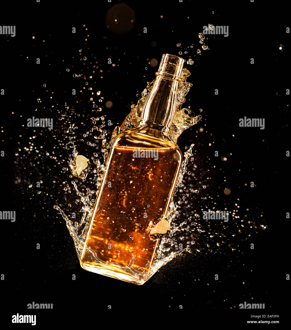 Concept of liquor splashing around bottle, isolated on black background Stock Photo