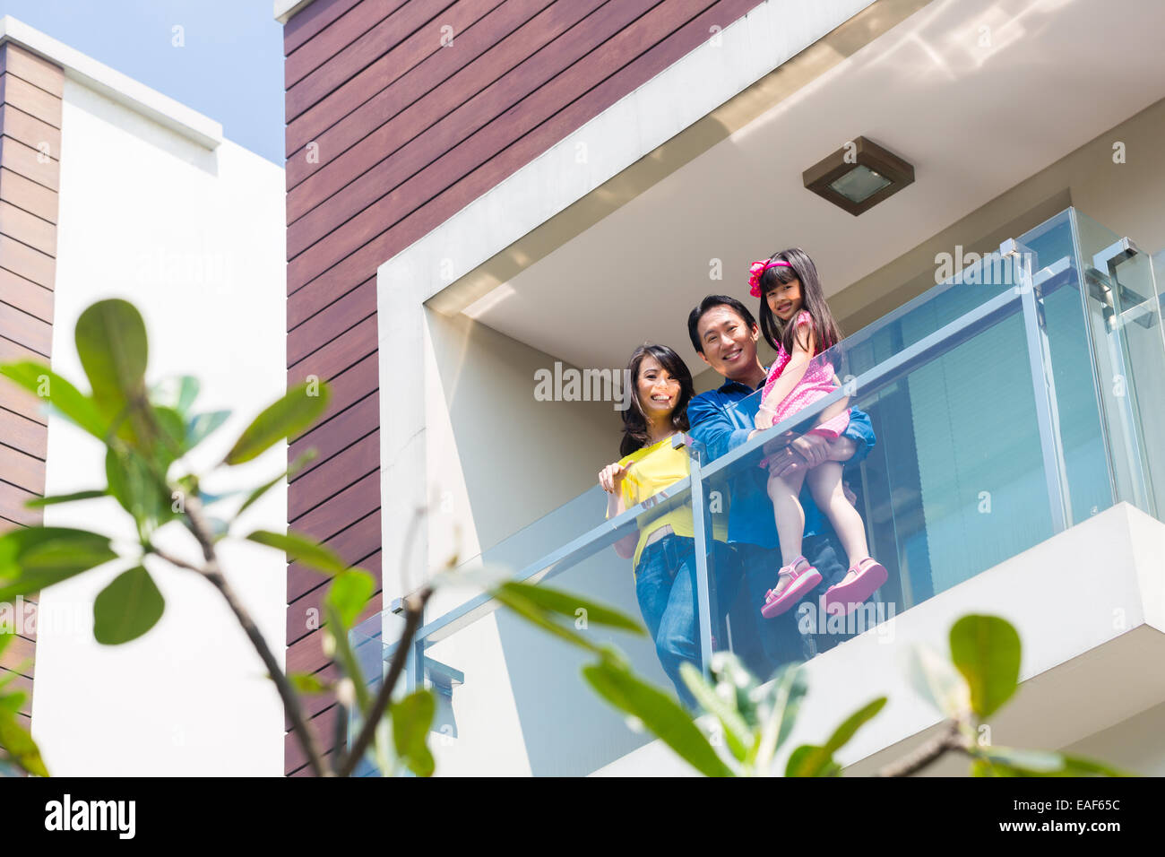 Asian Chinese family of parents and child standing proud on modern home balcony Stock Photo