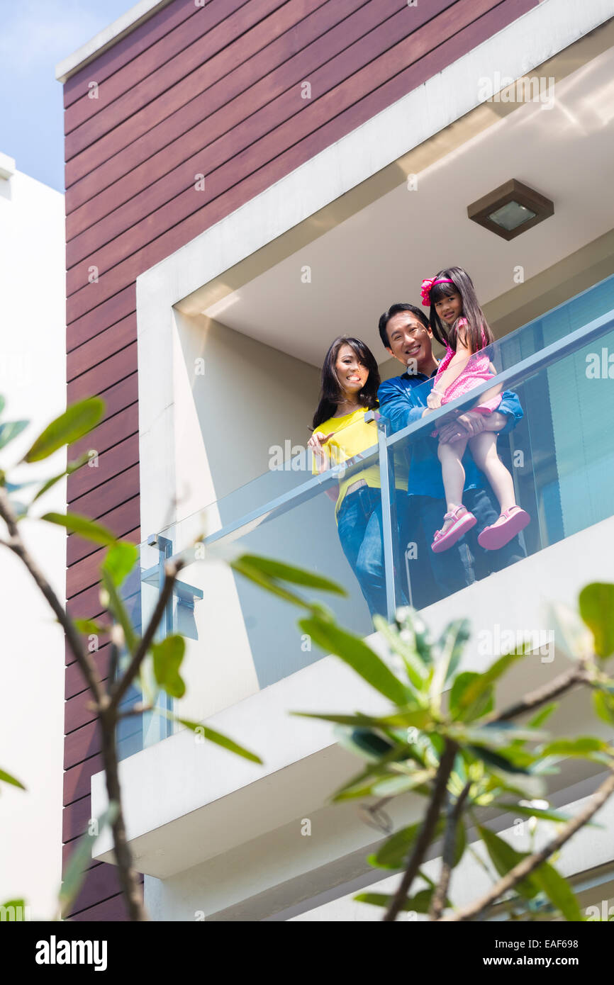 Asian Chinese family of parents and child standing proud on modern home balcony Stock Photo