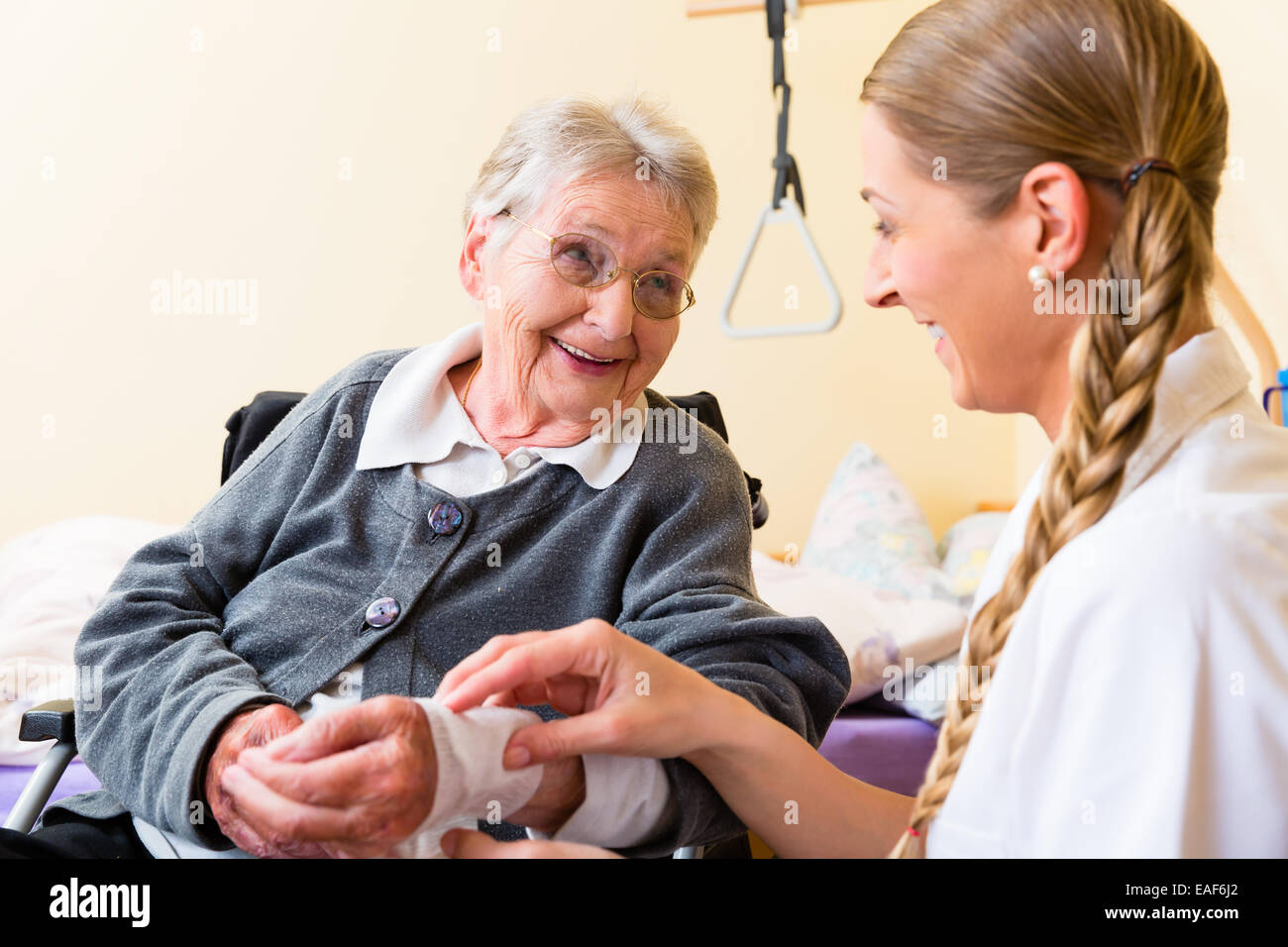 Nurse taking care of senior woman in retirement home bandaging a wound Stock Photo