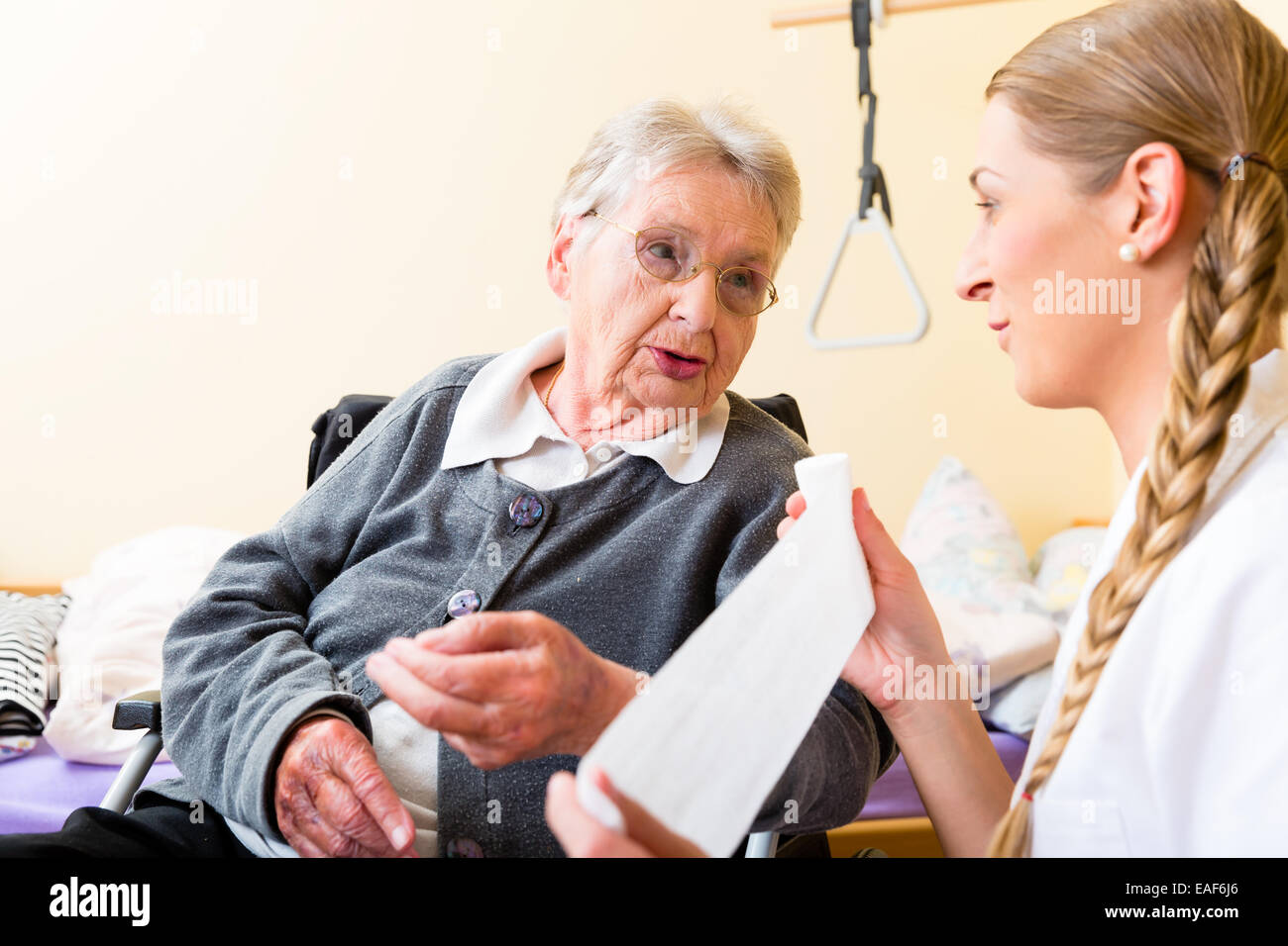 Nurse taking care of senior woman in retirement home bandaging a wound Stock Photo
