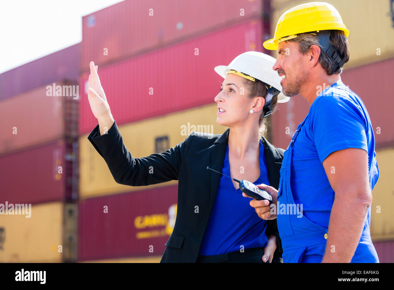 Freight shipping at container terminal of port, worker and manager discussing shipments Stock Photo