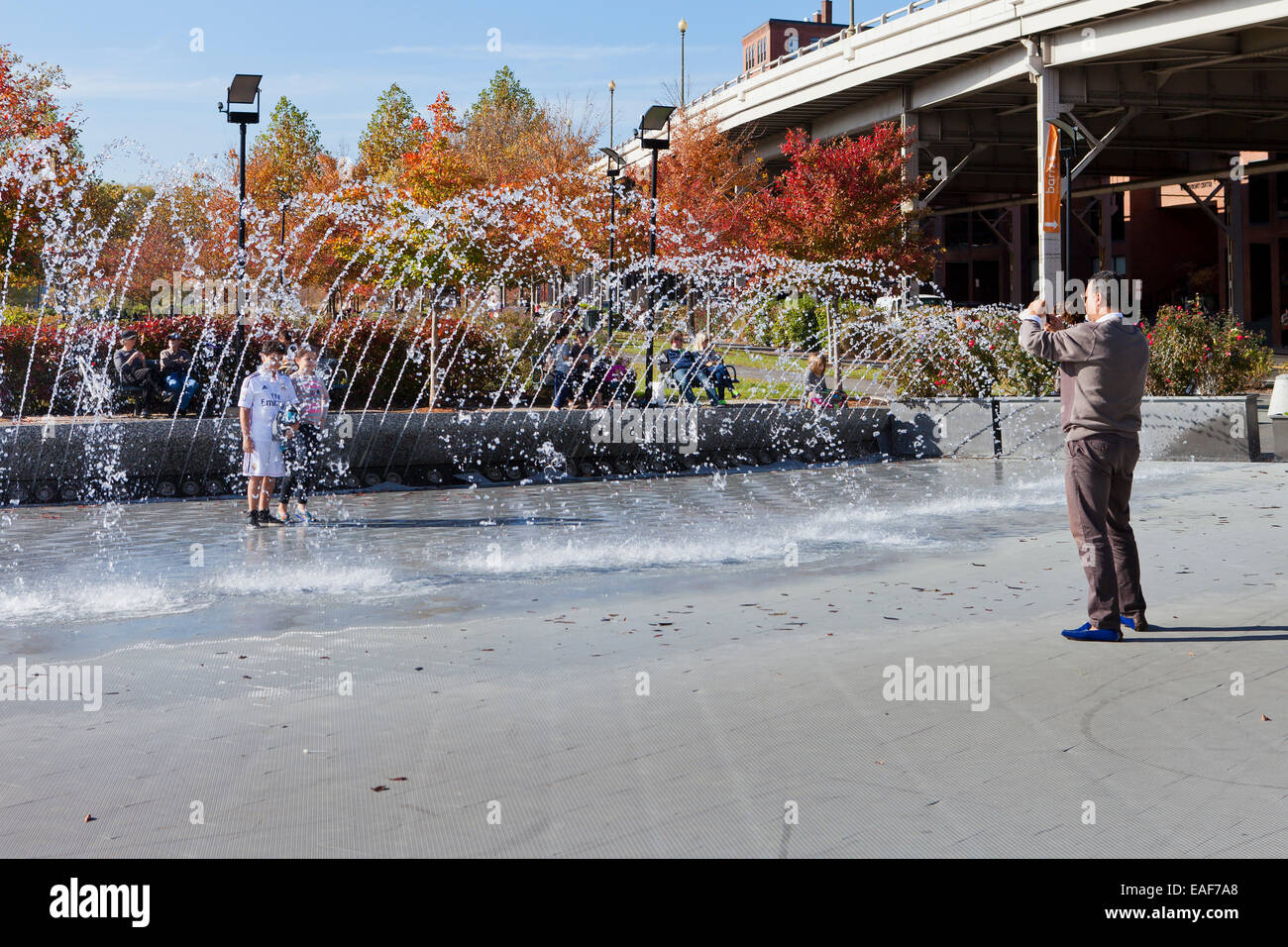Man taking pictures of children at play fountain - Georgetown, Washington, DC USA Stock Photo