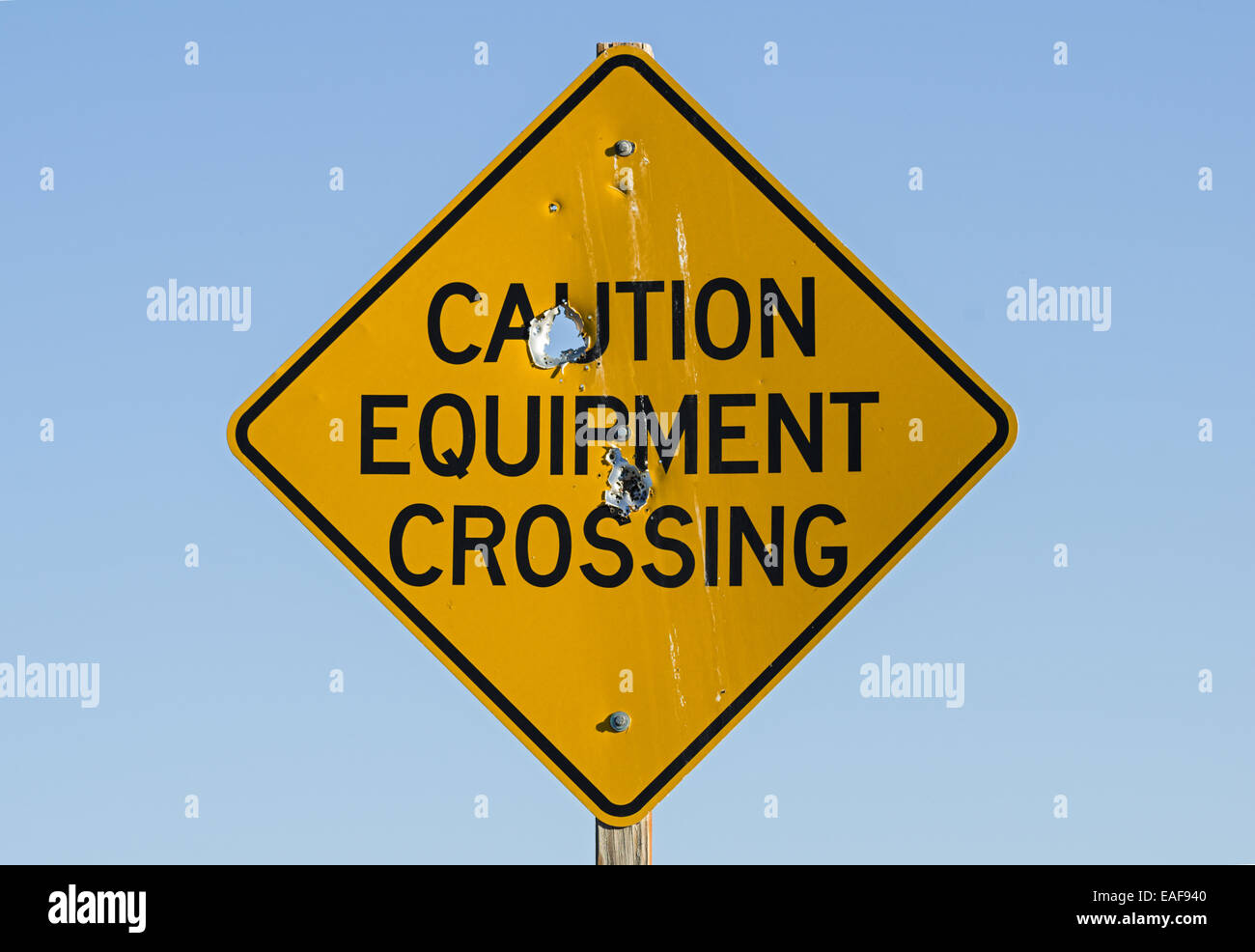 caution equipment crossing road sign with bullet holes Stock Photo