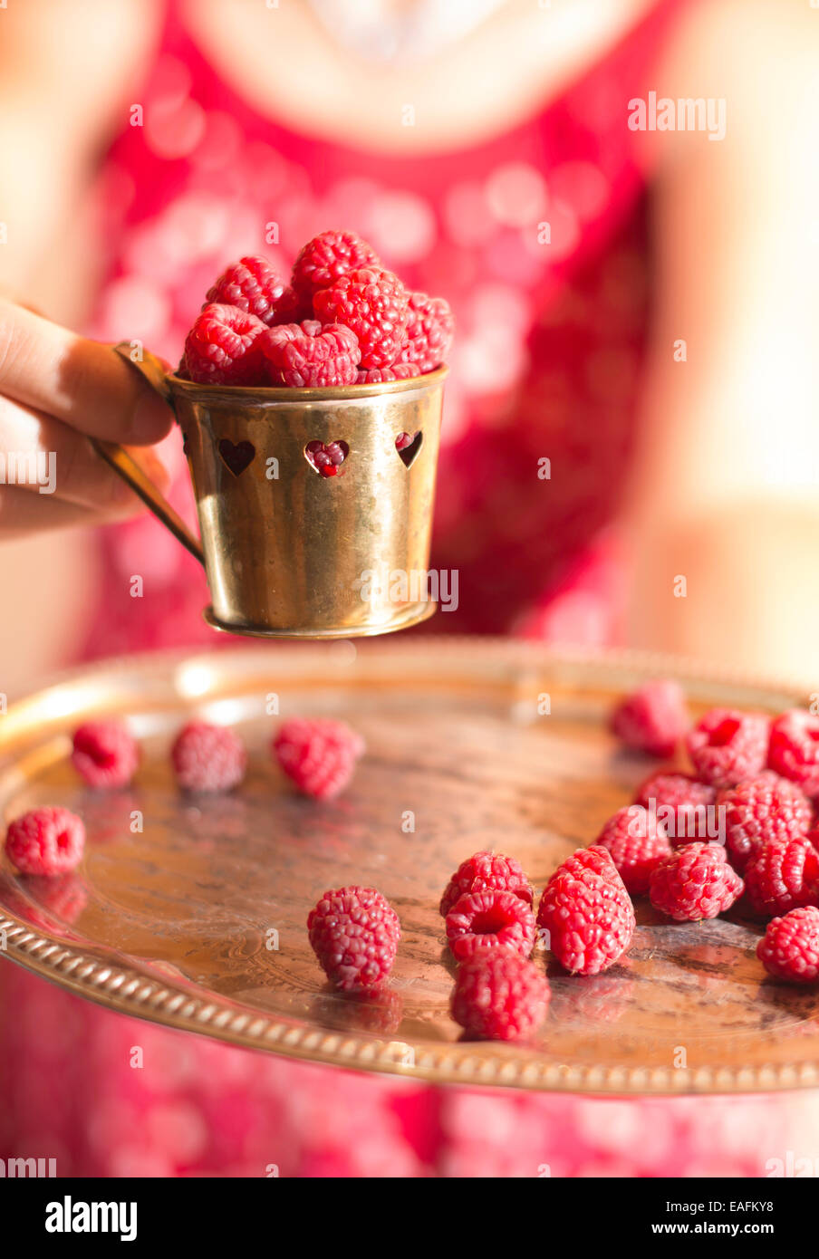 Woman in red dress holding a cup of raspberries Stock Photo - Alamy