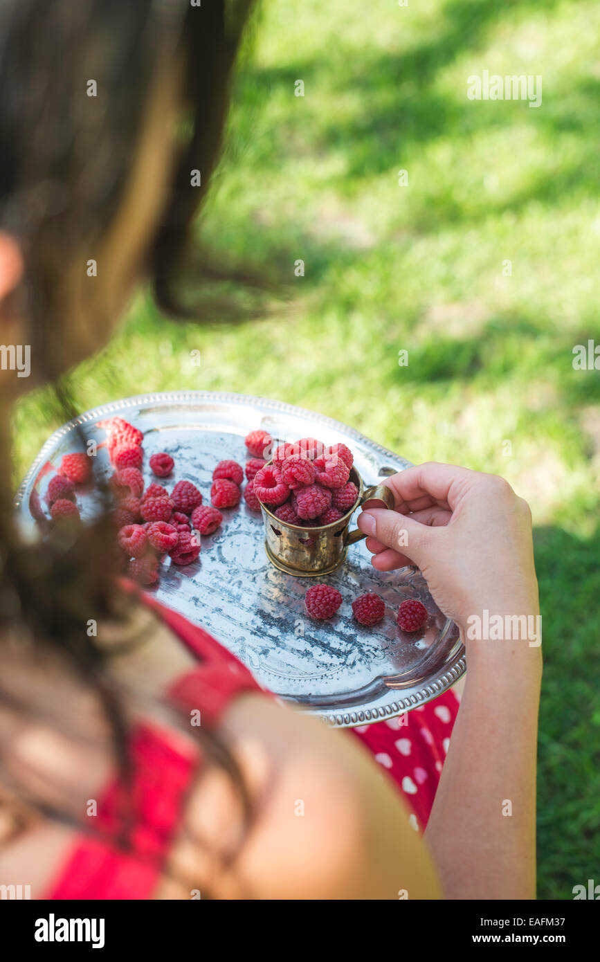 Woman in red dress holding a cup of raspberries Stock Photo - Alamy