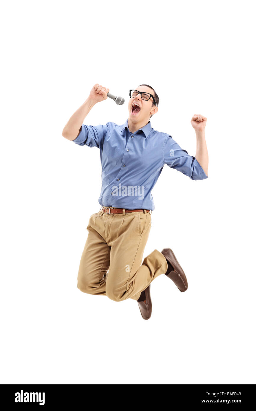 Excited guy singing on a microphone and jumping out of joy isolated on white background Stock Photo