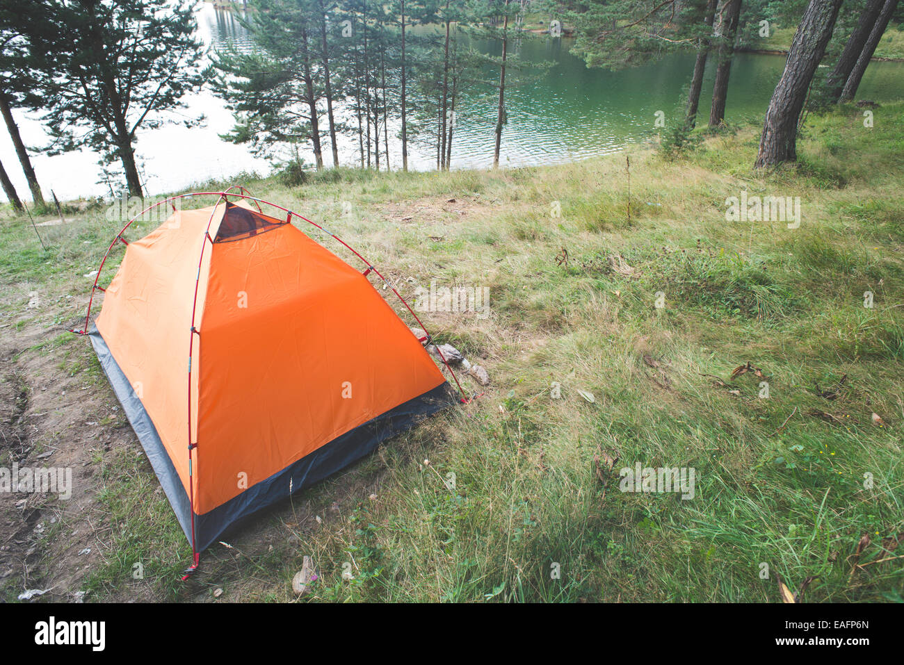 Tent in front of mountain dam. Trees Stock Photo