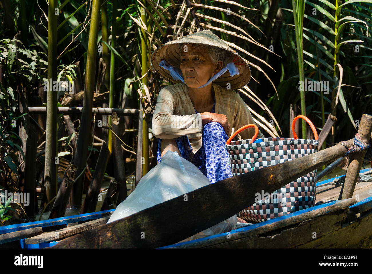 Vietnamese elderly woman seated in a traditional boat on Mekong River Stock Photo