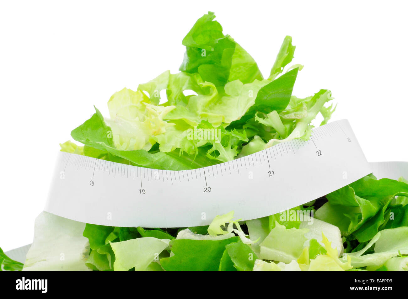closeup of a plate with a green salad and a measuring tape, symbolizing the dieting concept or to stay fit Stock Photo