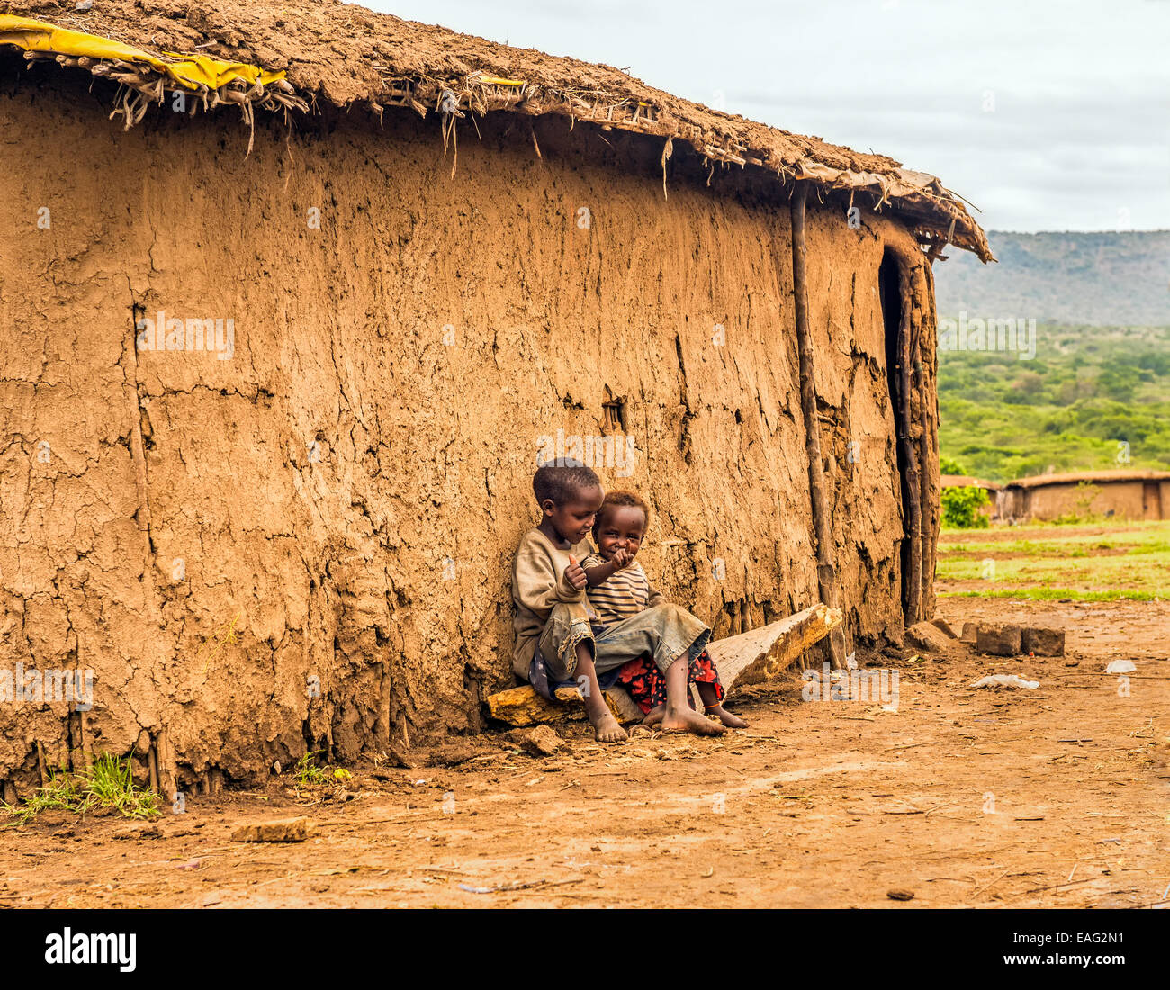 Two african boys sitting in front of a Masai tribe village house Stock Photo