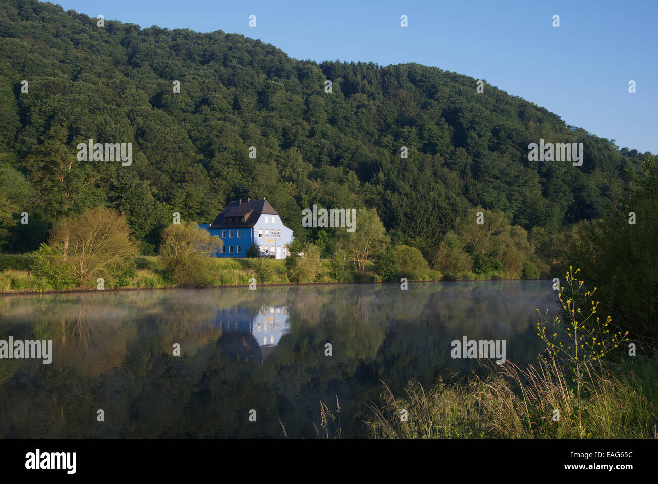 Early morning Saar River with blue house near Saarburg Saarland Germany Stock Photo