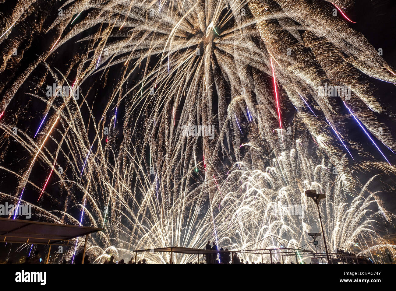 Fireworks fill the frame at this massive beach display in Benidorm Spain, with people silhouetted. Stock Photo