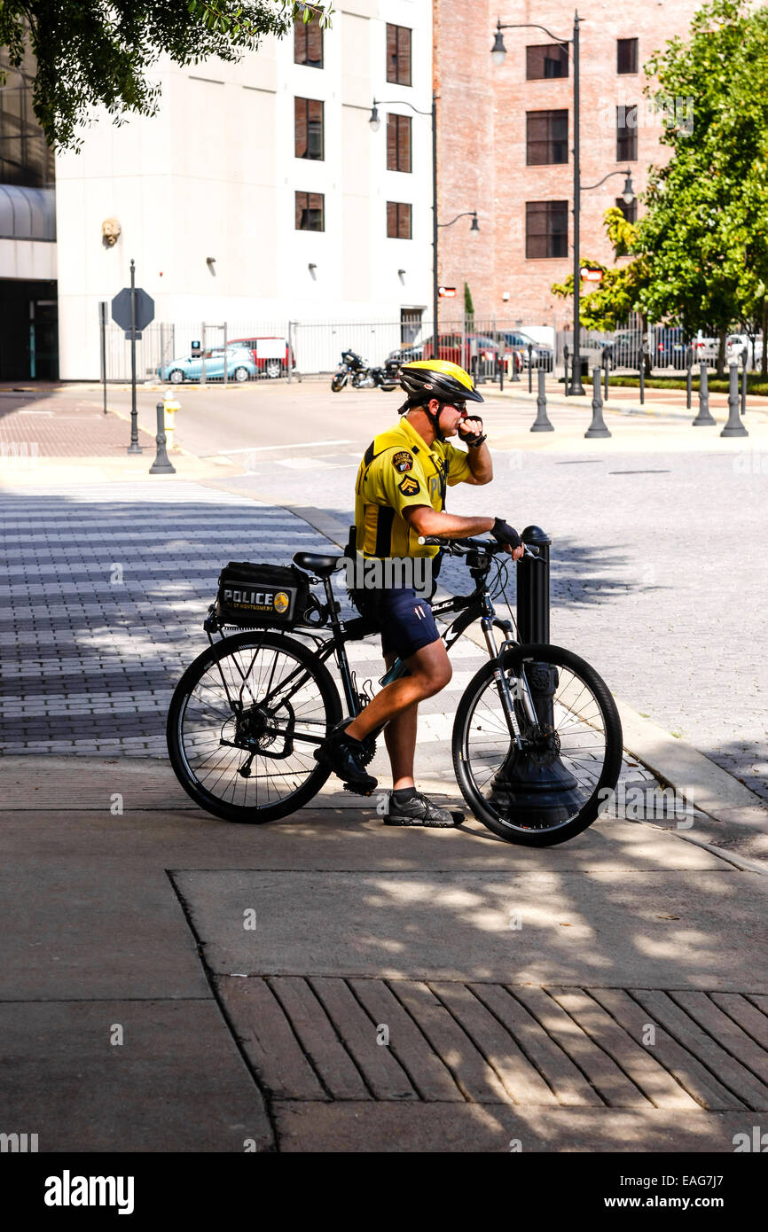 A yellow shirted bicycle cop in downtown Montgomery Alabama Stock Photo