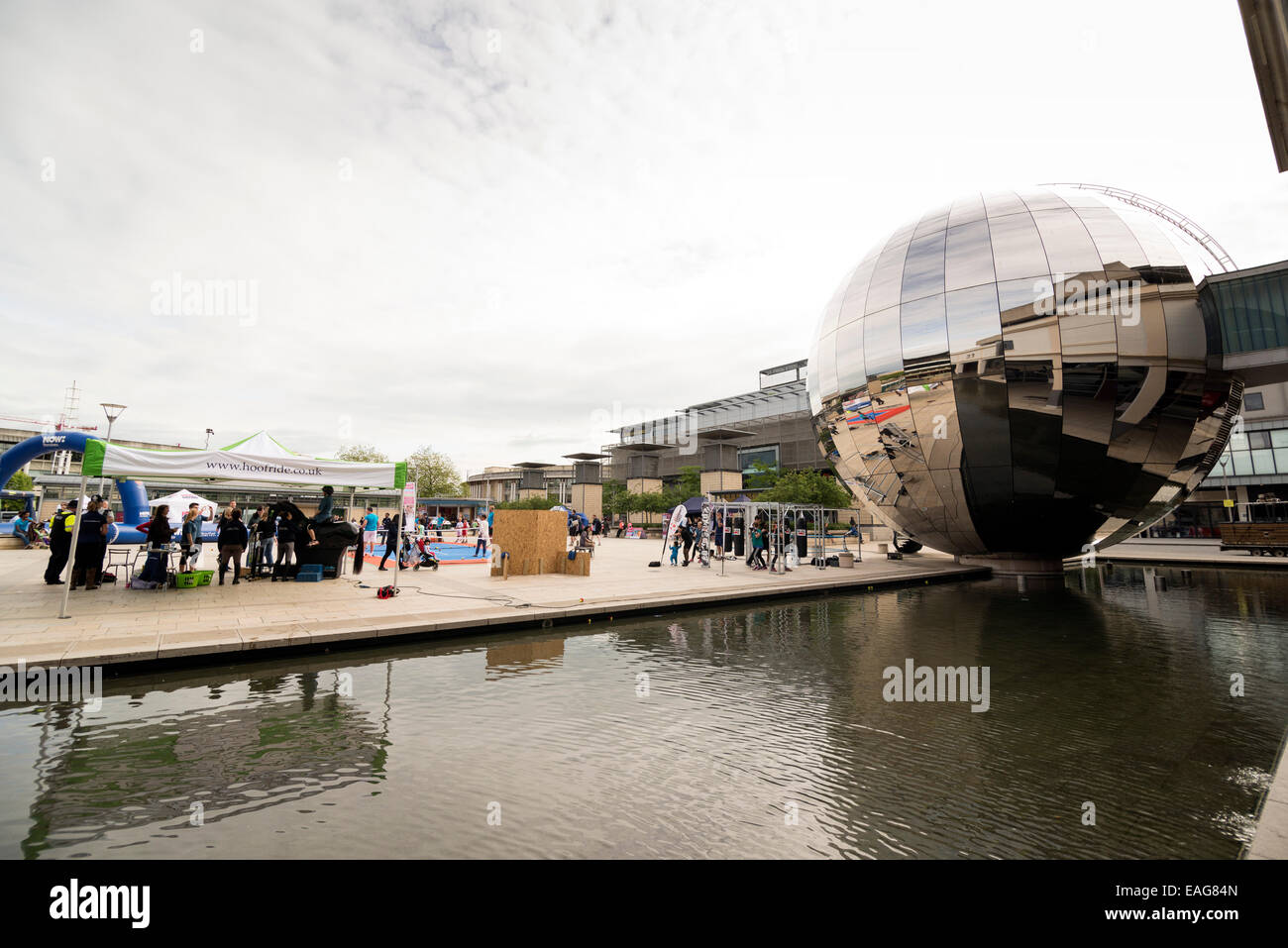BRISTOL, UNITED KINGDOM - JUNE 3, 2014: People enjoying the weather walk past the stainless-steel sphere of the planetarium, Mil Stock Photo
