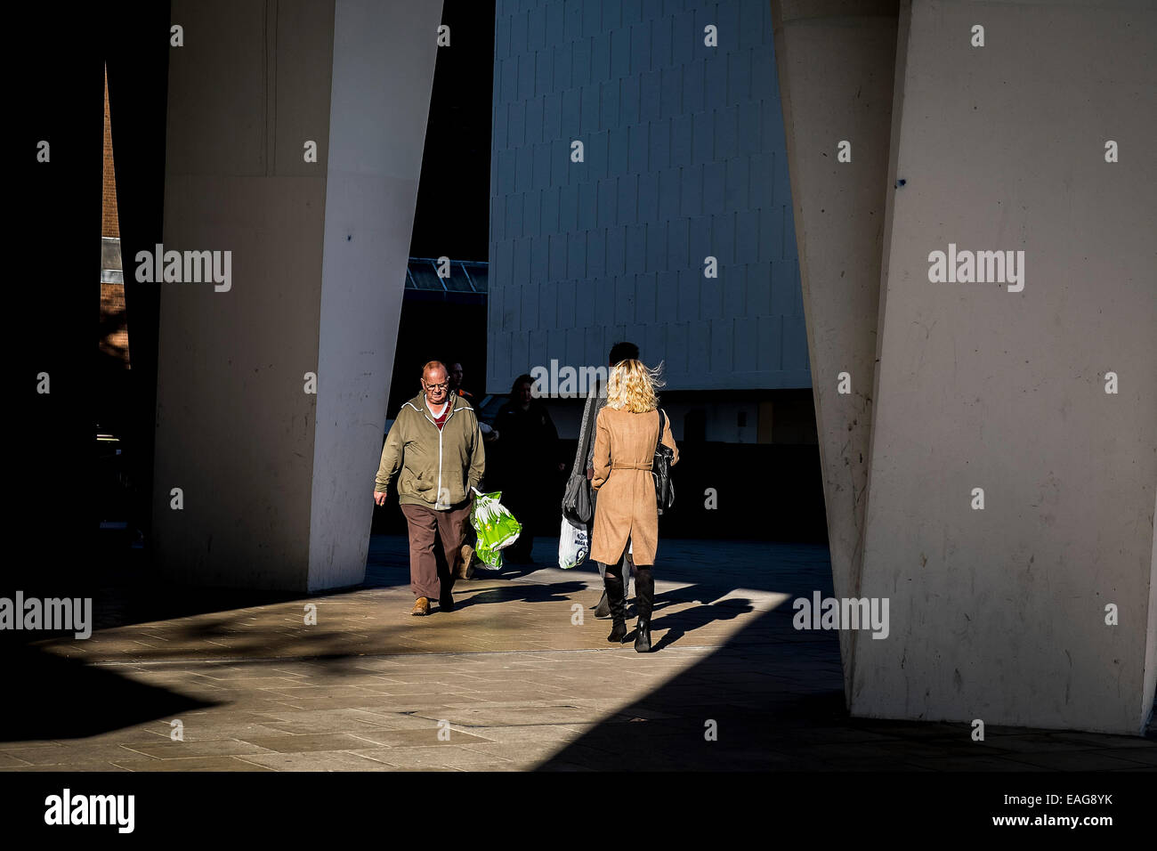 People walking into bright sunlight. Stock Photo