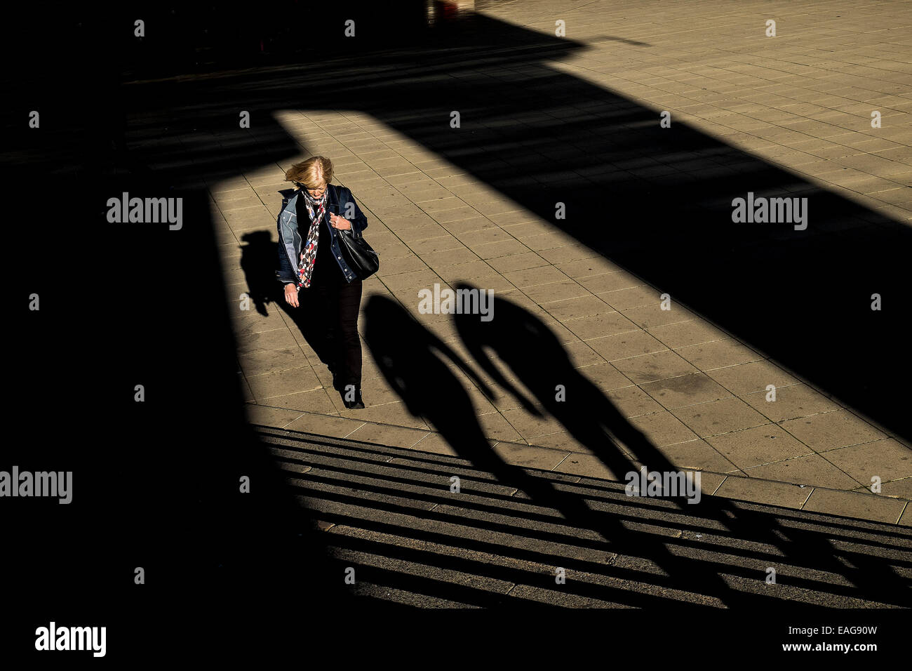A woman emerging from deep shadows into sunlight. Stock Photo