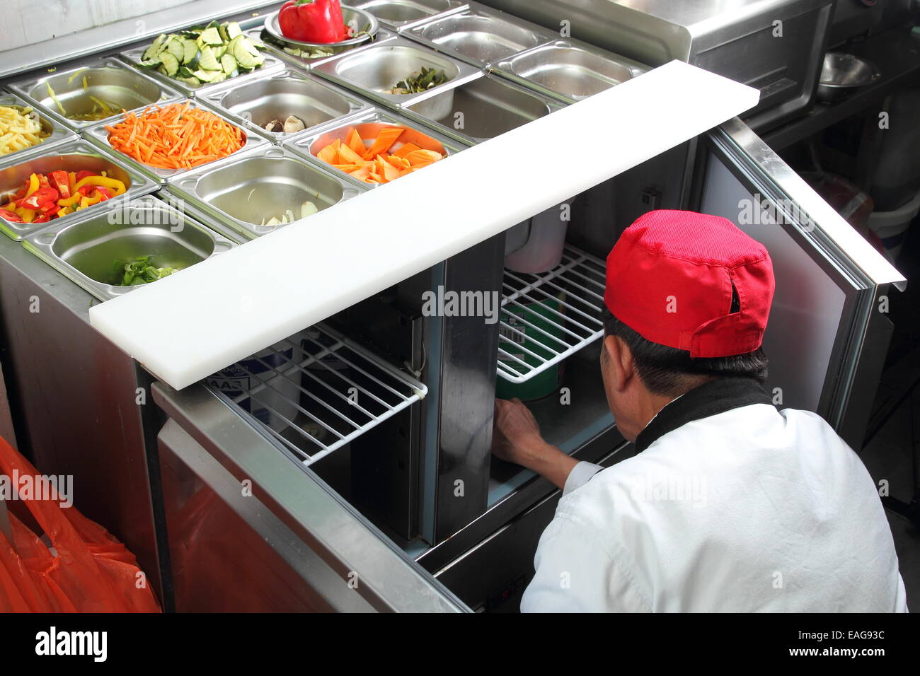 A Asian cook in a citchen working on a vegetable buffet bar Stock Photo