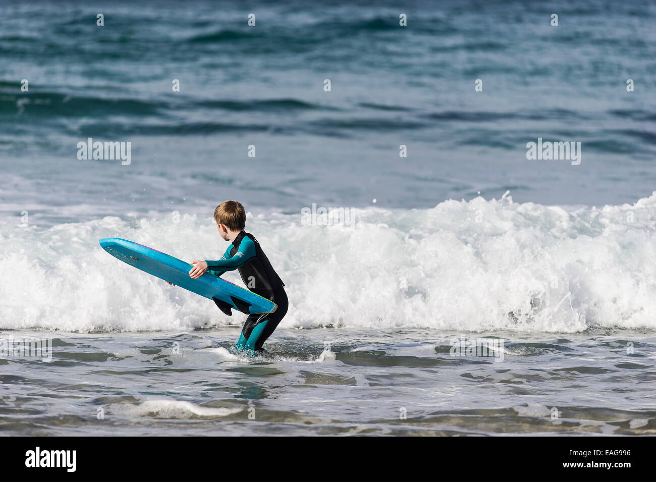 A young boy learning to bodyboard in the sea at Sennen Cove in Cornwall