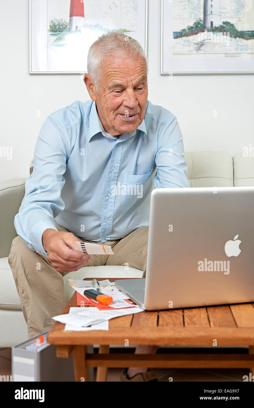 Senior sitting in front of a notebook and papers Stock Photo