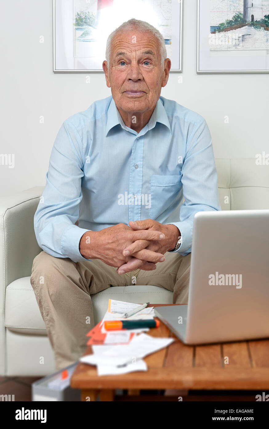 Senior sitting in front of a notebook and papers Stock Photo