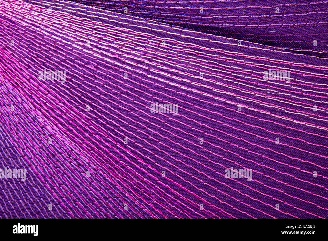 colorful stitching forming decorative pattern on mauve fabric Stock Photo