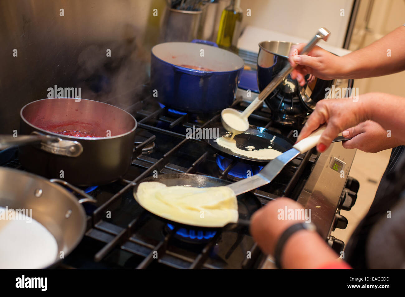 Two people making crepes on the stove Stock Photo