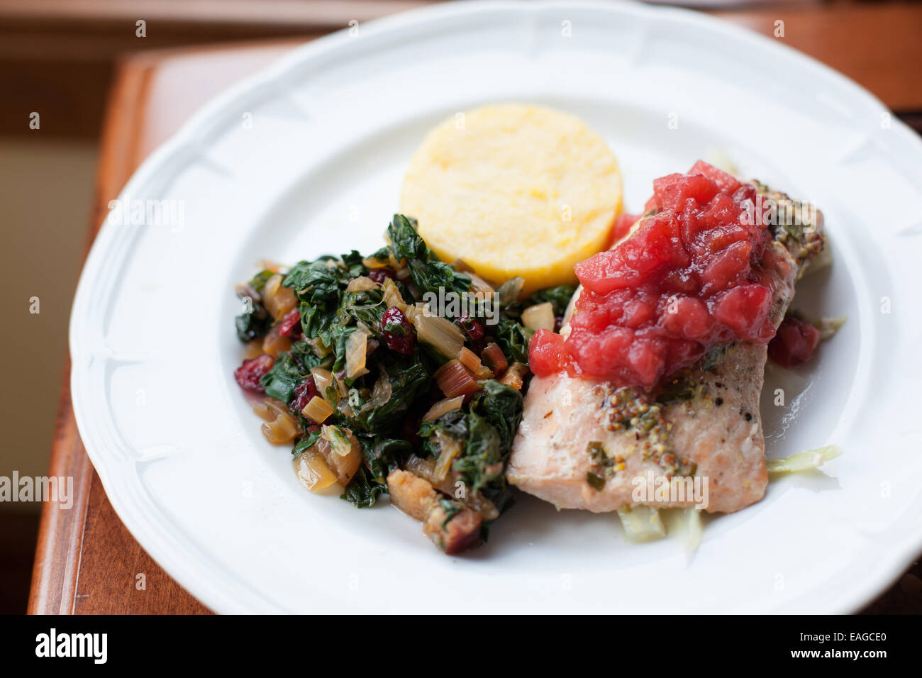 Salmon En Papillote with Tarragon Mustard Butter and Cranberry Apple Compote with Kale and Cheddar Polenta Stock Photo