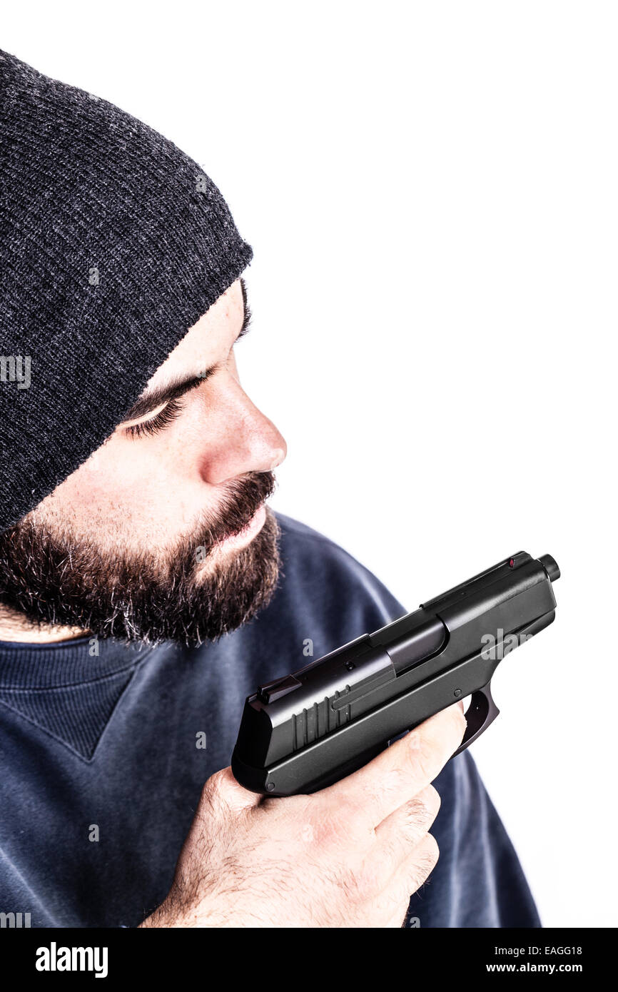 a bearded criminal or an undercover cop with a pistol and wearing a beanie hat isolated over white Stock Photo
